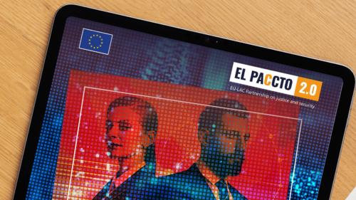 Ein Tablet auf einem Holztisch zeigt das Cover der Studie &bdquo;Hired By The Algorithm: How Criminal Networks Are Using AI To Recruit Across The EU, Latin America And The Caribbean&ldquo; von EL PACCTO 2.0 aus dem Jahr 2026. Das Cover zeigt zwei Personen vor einem digital verfremdeten Hintergrund und den Schriftzug &bdquo;We are hiring&ldquo;. 