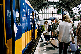 Eine Gruppe Personen am Bahnsteig steigt in einen Zug ein