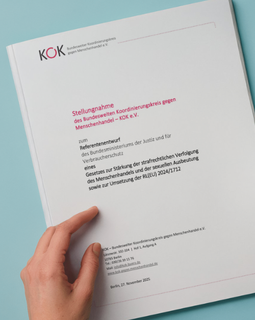 Eine Hand hält ein gedrucktes Dokument des KOK e. V. mit dem Titel Stellungnahme zum Referentenentwurf des Bundesministeriums der Justiz und für Verbraucherschutz zum Gesetz zur Stärkung der strafrechtlichen Verfolgung des Menschenhandels und der sexuellen Ausbeutung. Das Deckblatt zeigt das KOK Logo und formale Angaben, Hintergrund in hellem Blau.