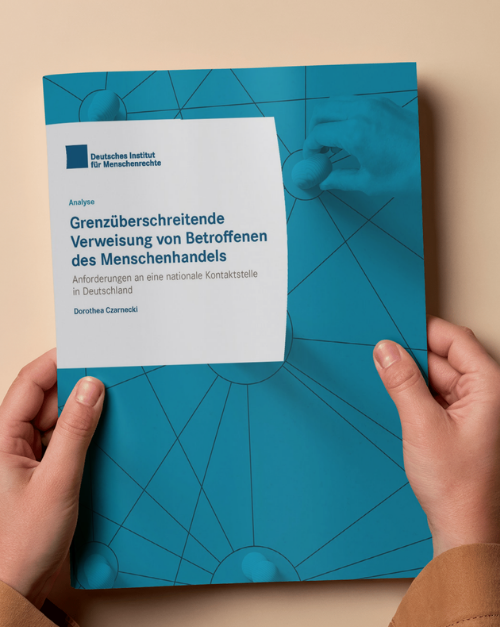Brosch&uuml;rencover in den H&auml;nden einer Person: blaue Publikation des Deutschen Instituts f&uuml;r Menschenrechte mit dem Titel &sbquo;Grenz&uuml;berschreitende Verweisung von Betroffenen des Menschenhandels&lsquo; und Untertitel &sbquo;Anforderungen an eine nationale Kontaktstelle in Deutschland&lsquo;.