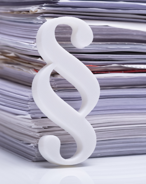 weißes Paragraph Zeichen vor einem großen Stapel Akten oder Papier